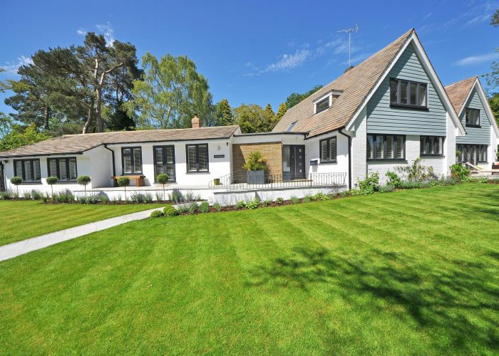 Contemporary house exterior with large manicured lawn and beautiful garden.